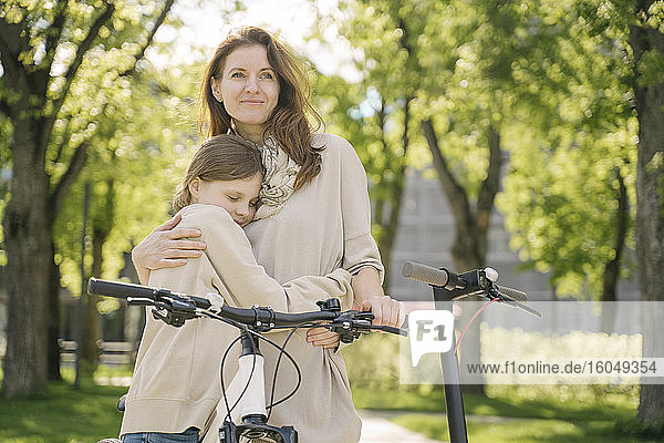 Mother and daughter embracing while spending leisure time in city park