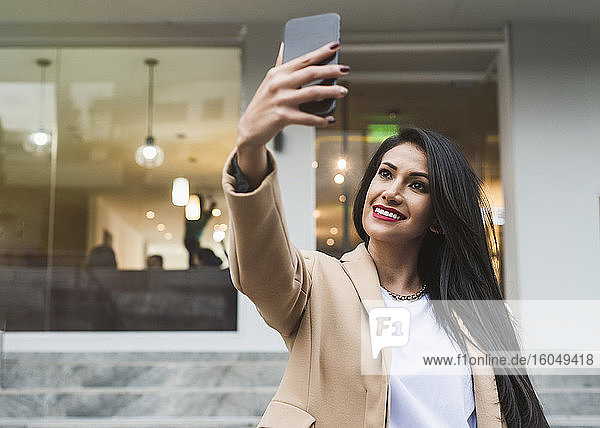 Frau macht ein Selfie mit ihrem Smartphone in der Stadt