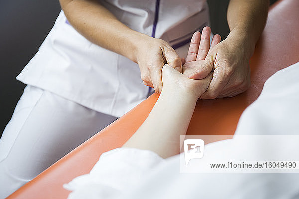 Die Hände einer Physiotherapeutin massieren die Hand einer Frau