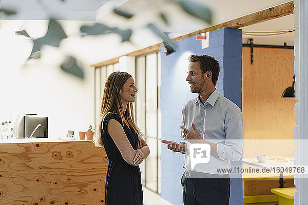 Geschäftsmann und Geschäftsfrau stehen in einem modernen Büro und unterhalten sich.