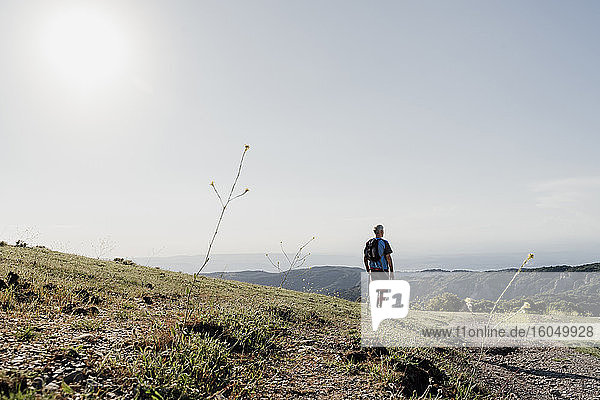 Active senior man standing while looking at landscape against sky