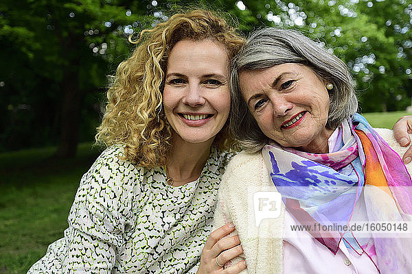 Happy senior woman sitting with blond daughter at home