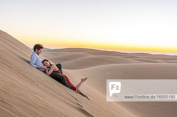 Glückliches Paar  das bei Sonnenuntergang in den Dünen liegt  Gran Canaria  Spanien