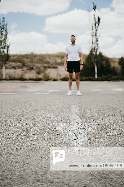 Male athlete standing at arrow sign on the road
