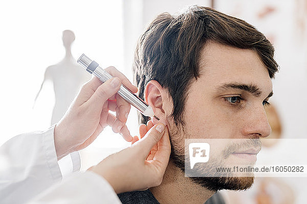 Heilpraktikerin gibt Mann Akupunktur mit Akupen im Ohr