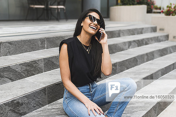 Frau mit Sonnenbrille benutzt Smartphone in der Stadt