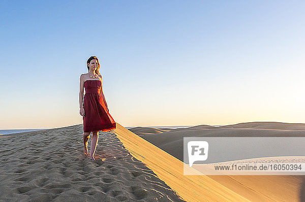 Woman in red dress walking at sunset in the dunes  Gran Canaria  Spain