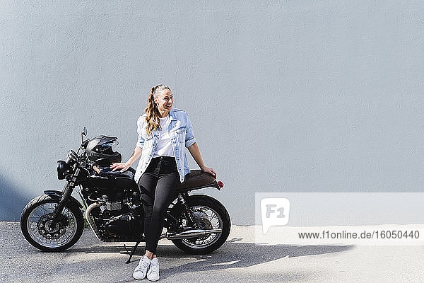 Lächelnde Frau auf Motorrad sitzend