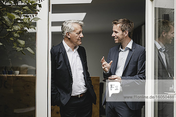 Two businessmen standing in office door  talking