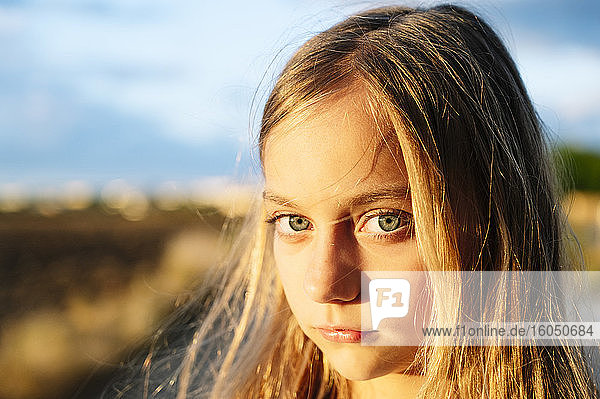 Blondes Mädchen starrt mit Sonnenlicht auf ihrem Gesicht