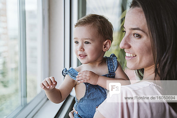 Mutter mit kleinem Mädchen zu Hause am Fenster