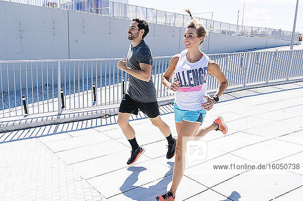 Glücklich fit Paar joggen auf der Straße der Stadt während des sonnigen Tages
