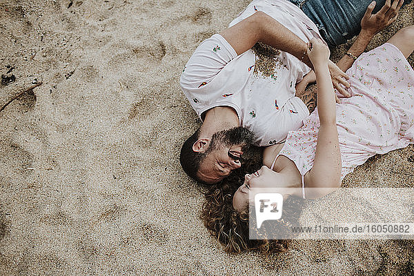 Lächelnder Vater und Tochter am Strand liegend