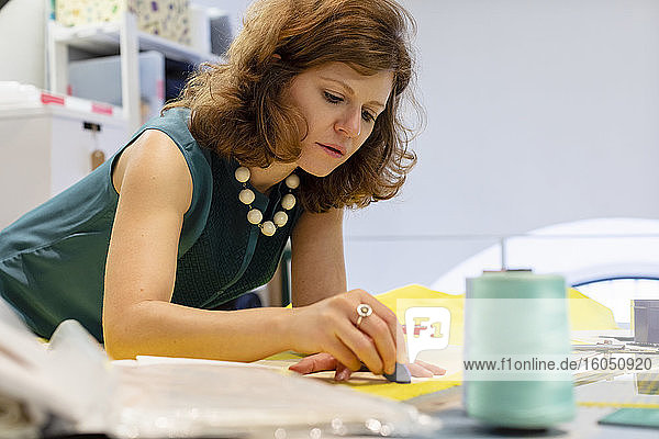 Modedesigner zeichnet im Atelier mit Kreide auf Stoff
