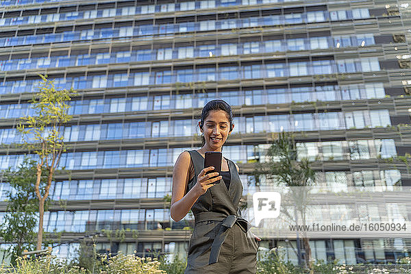Geschäftsfrau  die ein Mobiltelefon benutzt  während sie an einem Gebäude in der Stadt steht