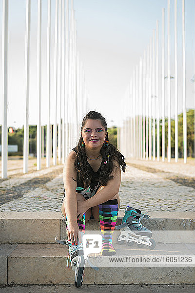 Teenager girl with down syndrome wearing 80s colorful make-up and roller skates