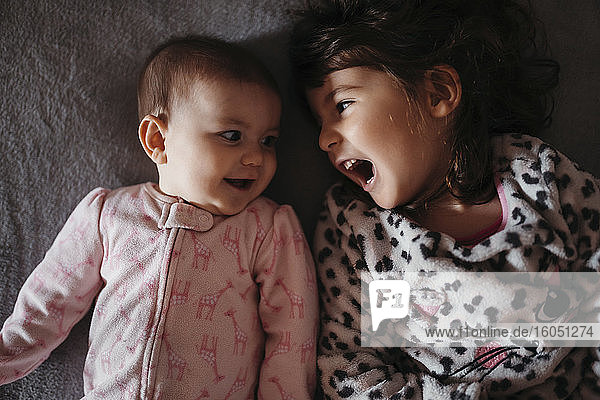 Girl screaming while looking at cute baby sister on bed
