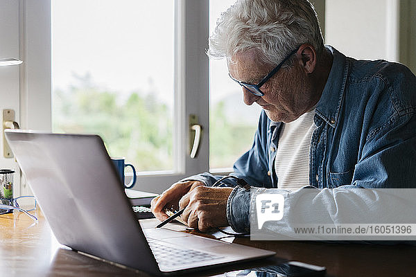 Senior man repairing laptop at home