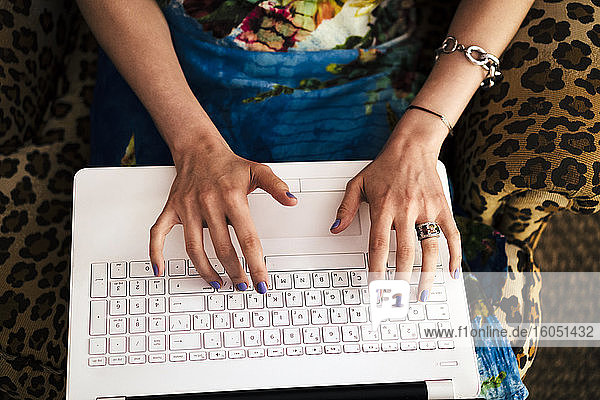 Nahaufnahme der Hände einer Frau  die zu Hause am Laptop arbeitet