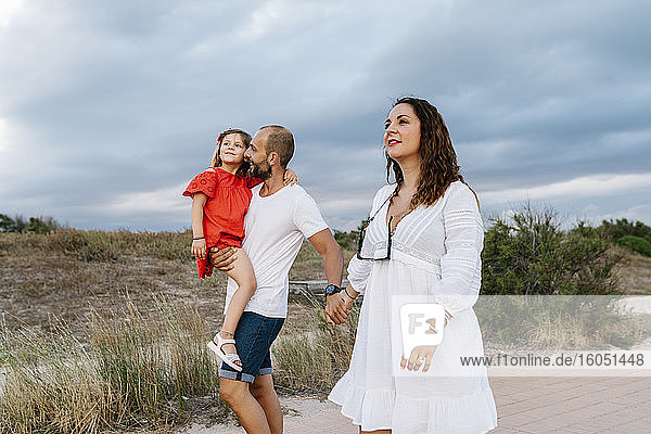 Family spending quality time at beach against cloudy sky