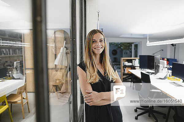 Young businesswoman standing in office  with arms crossed