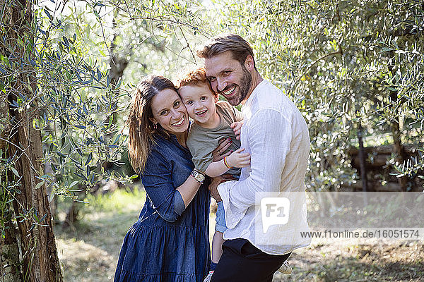 Glückliche Familie  die sich an den Pflanzen im Olivenhain erfreut