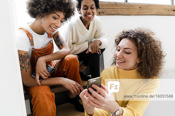 Three friends having fun with smartphone at home