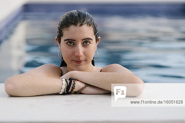 Porträt eines nassen Teenagers  der sich am Pool anlehnt