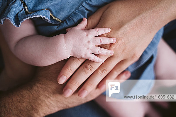 Baby girl's hand on father and mother at home