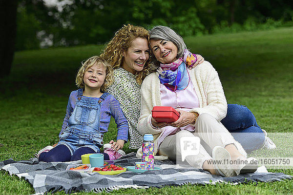Glückliche Frauen der dritten Generation genießen ein Picknick im öffentlichen Park