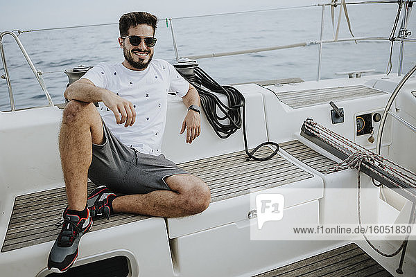 Lächelnder junger Mann mit Sonnenbrille auf einem Segelboot