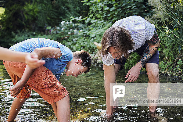 Mann erkundet mit Junge im Bachwasser im Wald