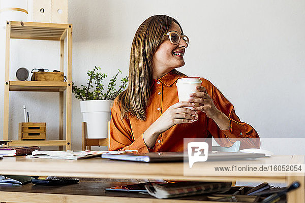 Female freelancer at home sitting at desk having a coffee break