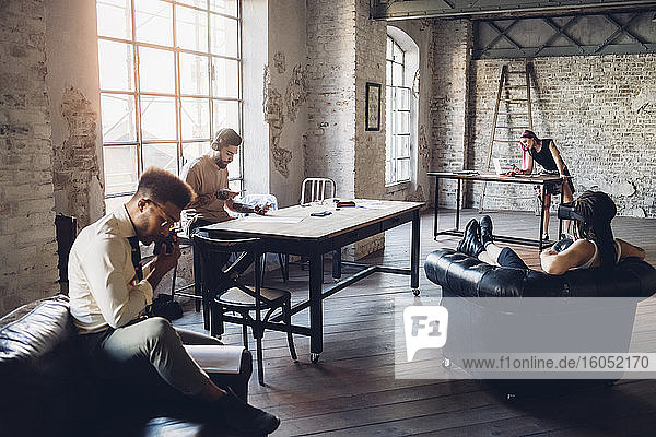 Creative team in loft office using technological devices