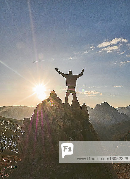 Silhouette eines männlichen Wanderers  der mit ausgestreckten Armen auf einem Berg bei Sonnenuntergang steht  Leon  Spanien