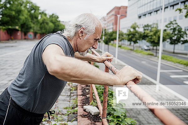 Älterer Mann trainiert auf einem Geländer in der Stadt