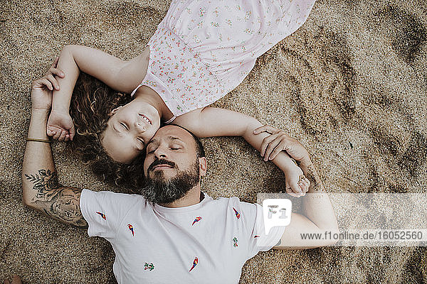 Tochter mit Vater am Strand liegend
