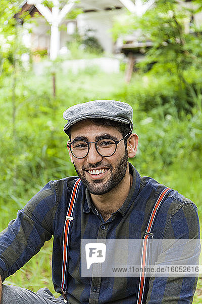 Portrait of smiling young man wearing glasses and cap