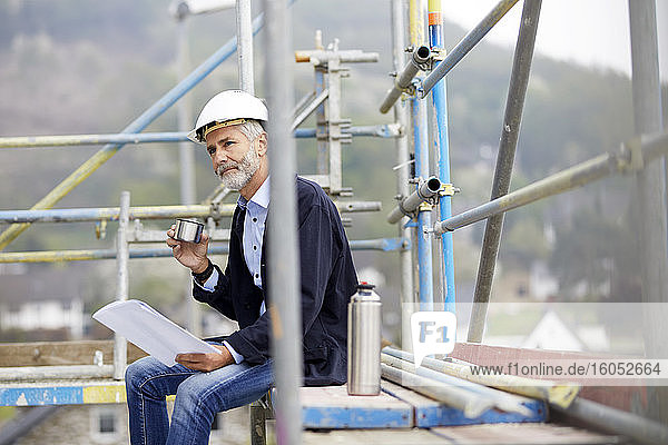 Architect having a break on scaffolding on a construction site