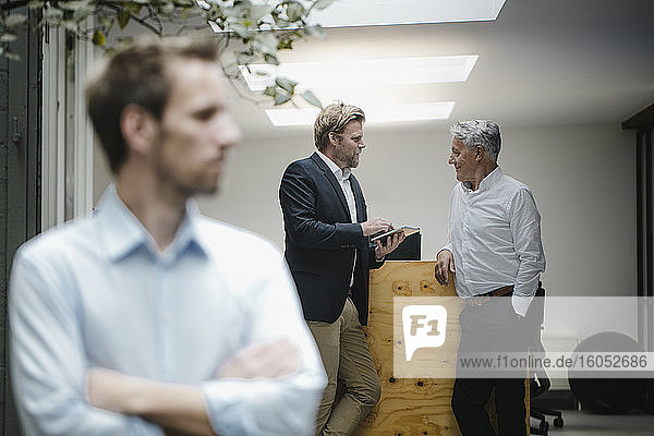 Business people talking in office  businessman standing in front  listening sceptically