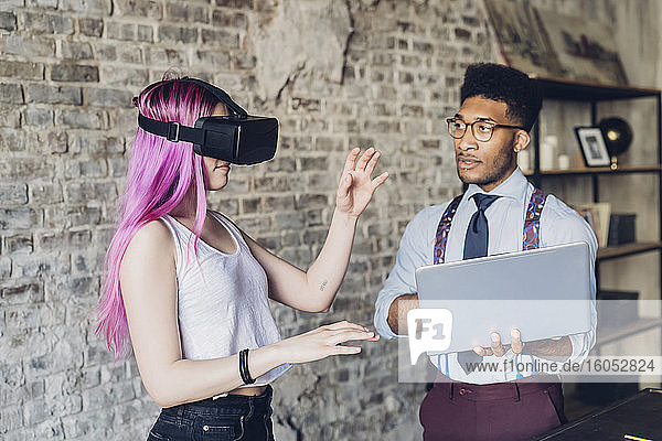 Zwei kreative Geschäftsleute mit VR-Brille und Laptop im Loft-Büro