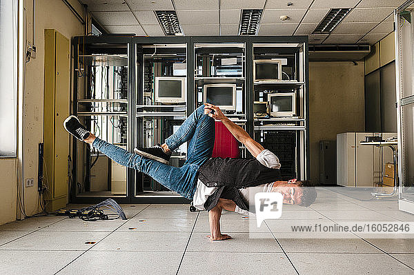 Young man breakdancing on floor in abandoned room