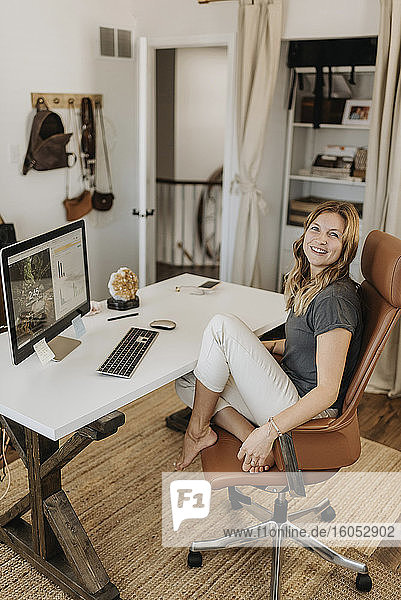 Smiling woman sitting on chair while working at home