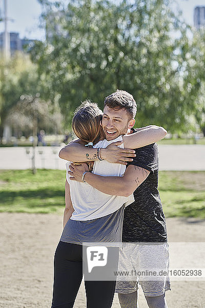 Ein sich umarmendes Paar vor dem Training im Park