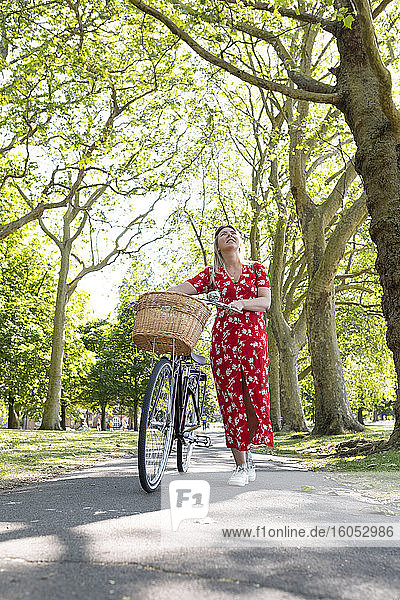 Nachdenkliche Frau mit Fahrrad auf dem Fußweg im Park
