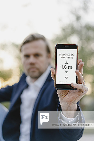 Close-up of businessman holding smartphone showing distance on display