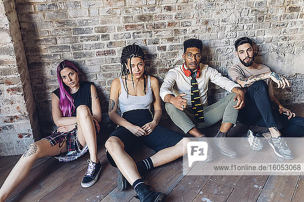Portrait of group of friends sitting on the floor in a loft
