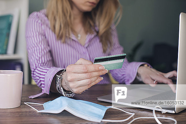 Geschäftsfrau mit Kreditkarte bei der Online-Zahlung über einen Laptop im Büro