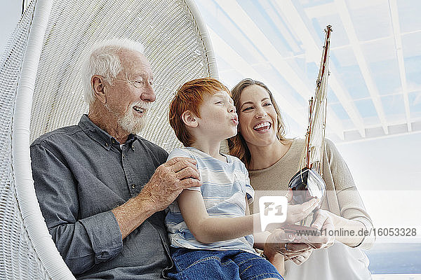 Glücklicher Großvater  Mutter und Sohn mit Modellsegelschiff im Hängesessel