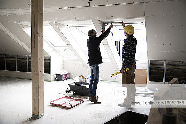 Architekt und Bauarbeiter diskutieren über Fensterrahmen bei der Renovierung eines Hauses